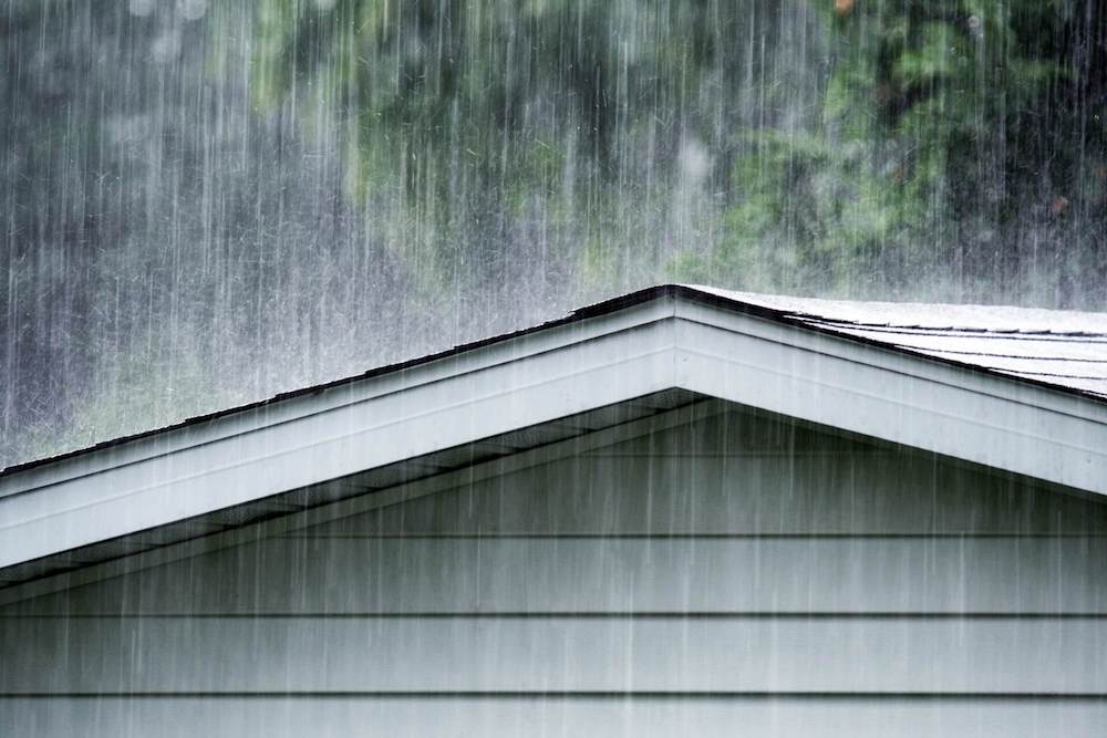 Heavy rain hitting a house roof.